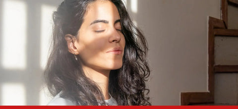 Donna con occhi chiusi che assorbe la luce solare, fonte naturale di Vitamina D per il benessere.
